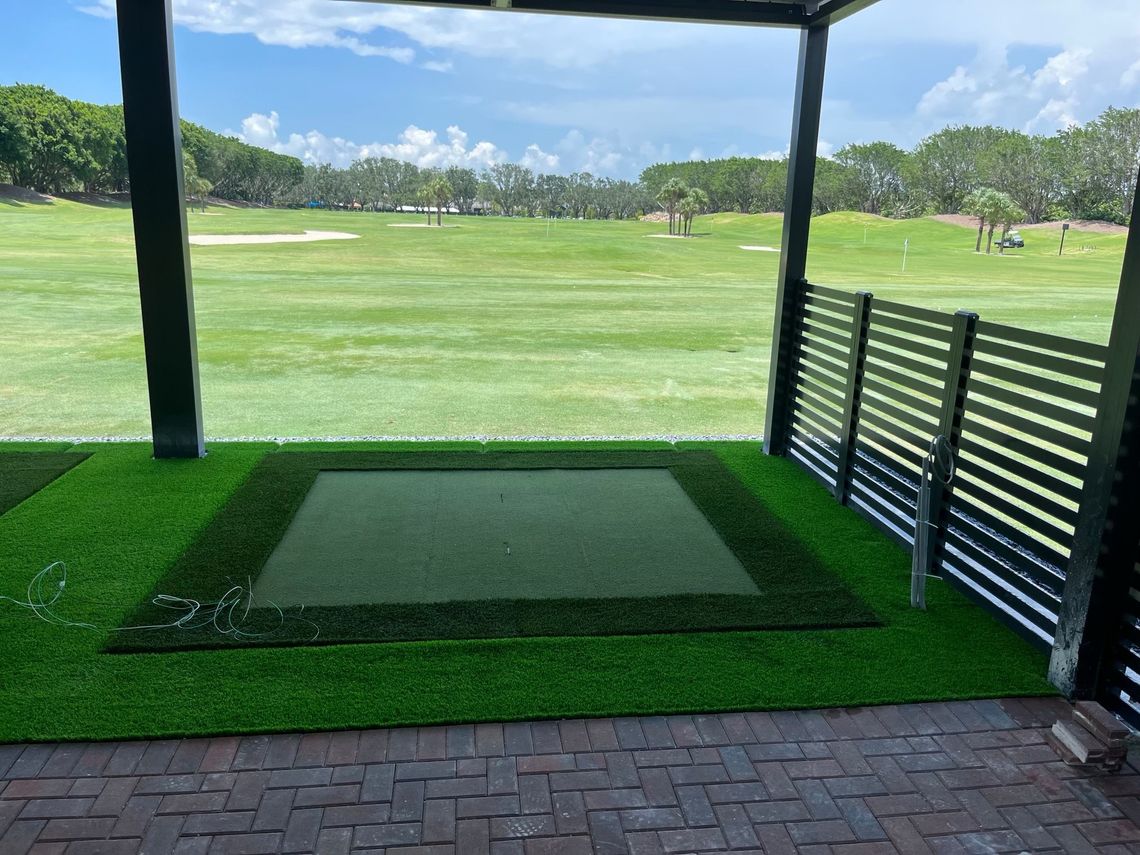 Artificial turf hitting bay facing a practice range