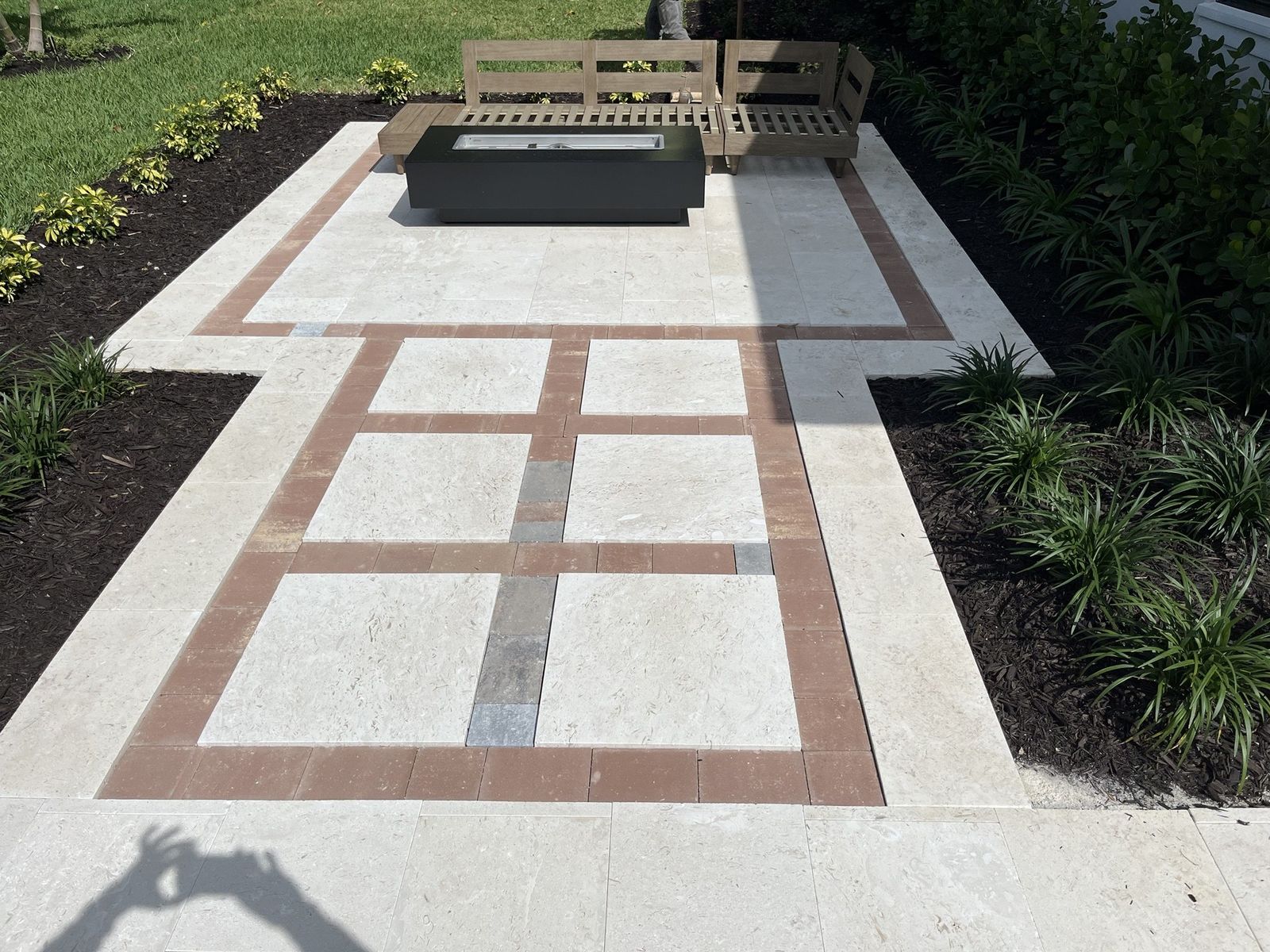 Stone patio with brick bands between the slabs, before the turf inlay