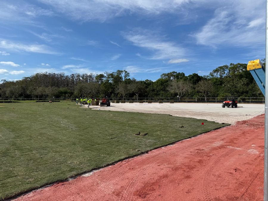 Crew laying sod across a ballfield outfield
