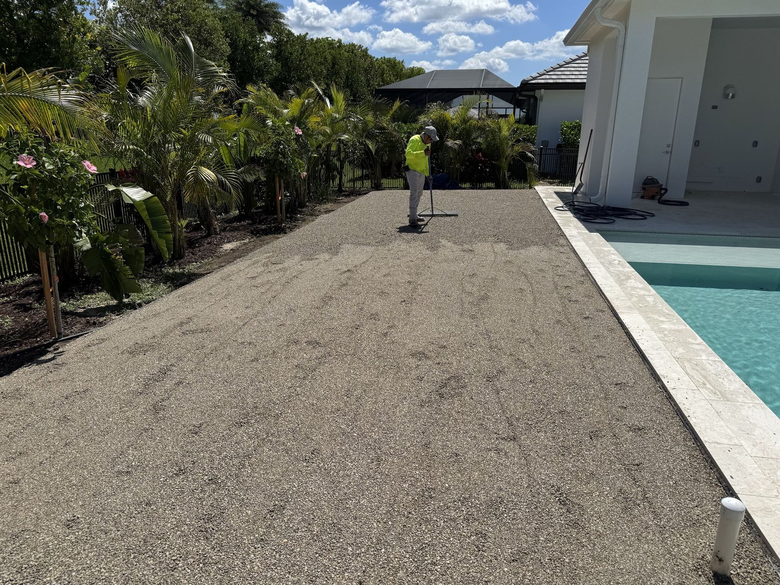 Crew raking a crushed-stone base beside a pool